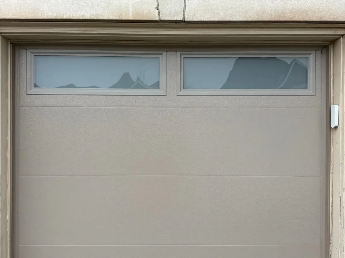 Beige flush-panel garage door with glass inserts — Etobicoke